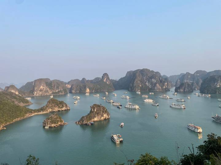 Vue aérienne de la baie d'Halong avec de nombreux bateaux éparpillés sur l'eau.