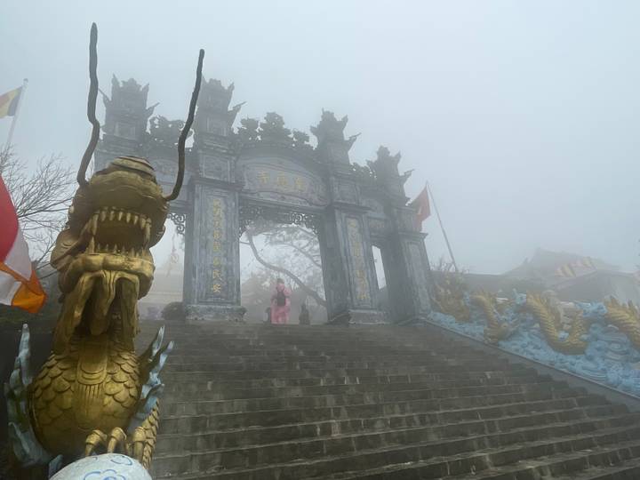 Entrée de temple embrumée ornée de dragons.