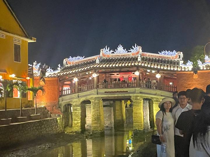 Pont traditionnel éclairé aux lanternes la nuit avec des gens.