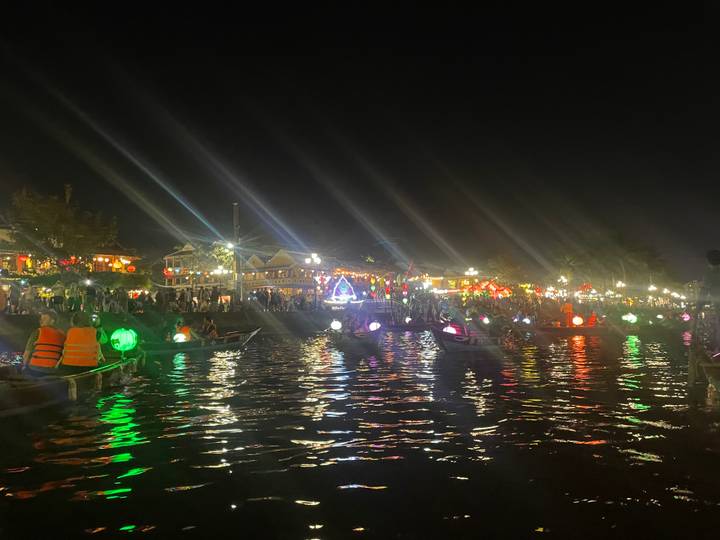 Marché nocturne au bord de l'eau avec des lumières colorées et des reflets.
