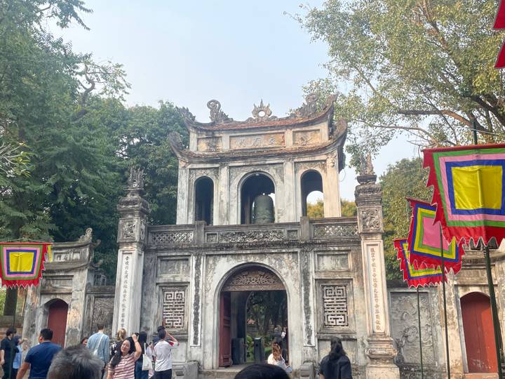 Entrée de temple avec drapeaux décoratifs et arbres.