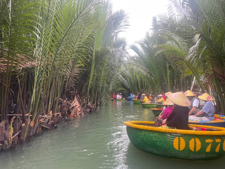 Des touristes dans des bateaux en osier flottant à travers une végétation luxuriante.