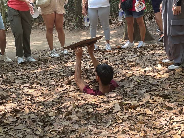 Homme émergeant d'un tunnel souterrain ; groupe qui regarde.