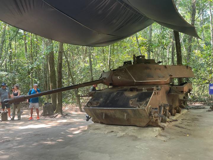 Char abandonné dans une zone forestière avec des touristes qui observent.