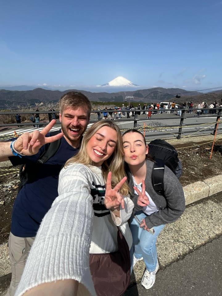 Trois personnes qui prennent un selfie avec un arrière-plan montagneux.