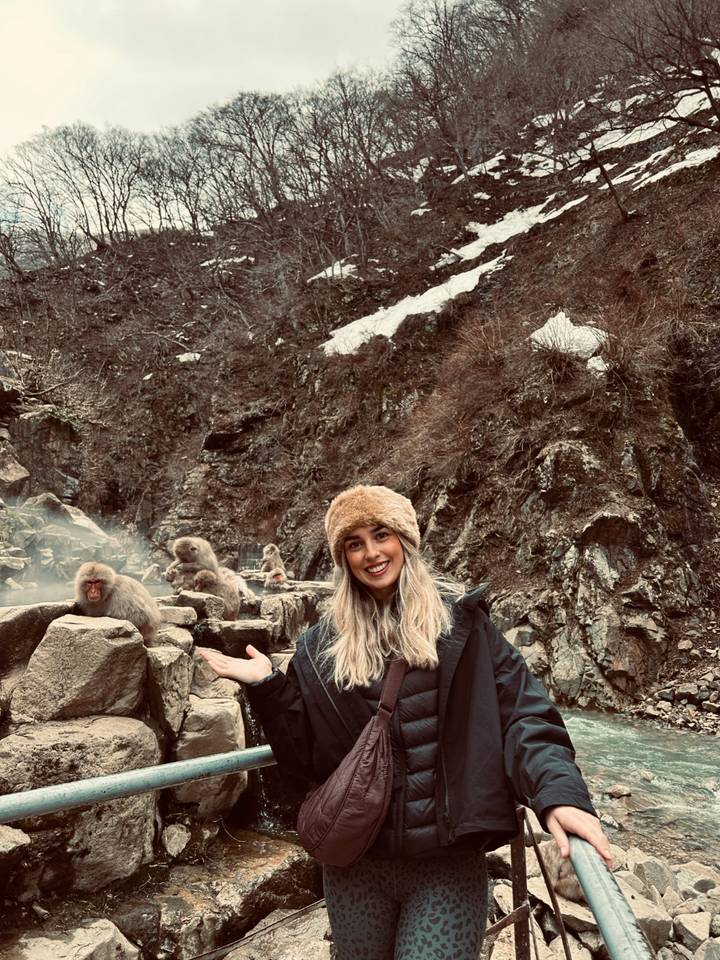 Personne debout parmi des macaques japonais dans une source chaude.