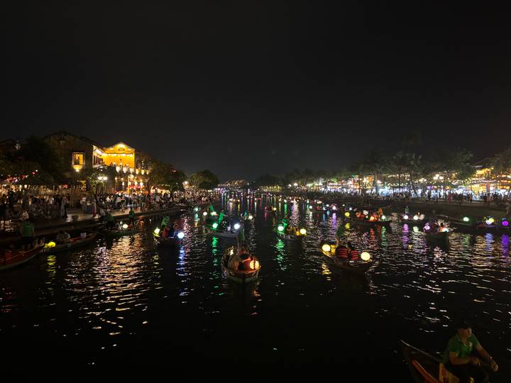 Boats with illuminated lanterns on a river at night.