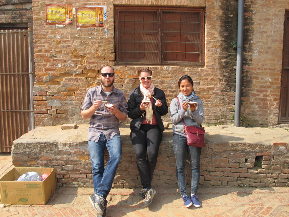 Trois personnes assises sur un mur de pierre dégustant des amuse-gueules.