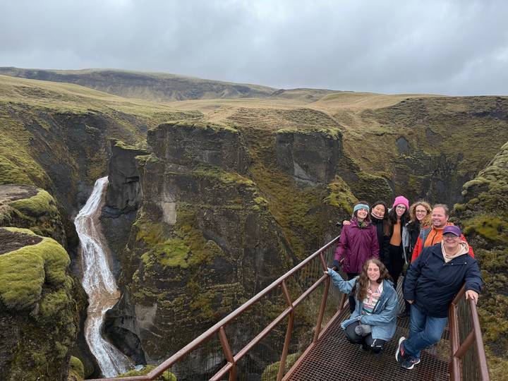Groupe de personnes posant sur un pont avec un canyon moussu en arrière-plan.
