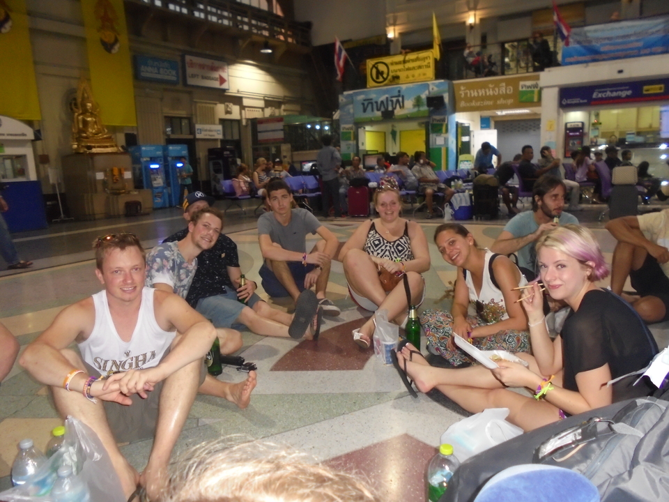 Group of people sitting on the floor in a busy indoor space.