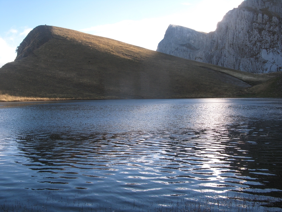 Lac calme entouré de collines dans une région isolée.