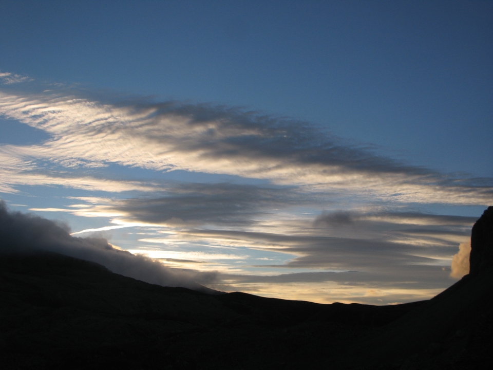 Nuages et ciel au coucher du soleil avec des silhouettes de montagnes.