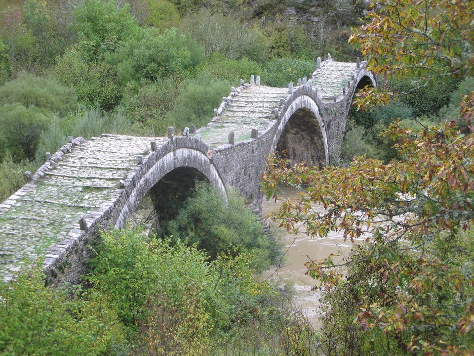Pont de pierre enjambant une rivière dans une vallée luxuriante.