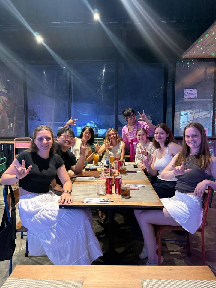 Groupe d'amis faisant des signes de la main à une table de restaurant.