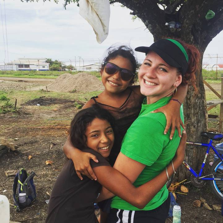 Person embracing two smiling children.