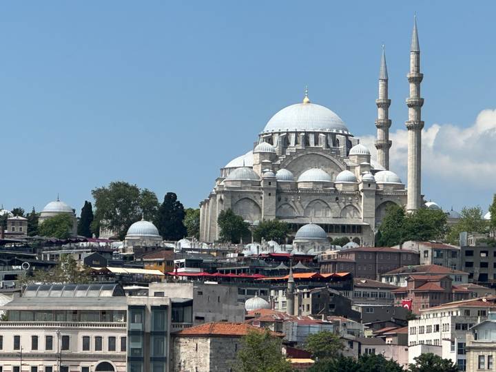 Grande mosquée avec plusieurs dômes et minarets dominant le paysage urbain.
