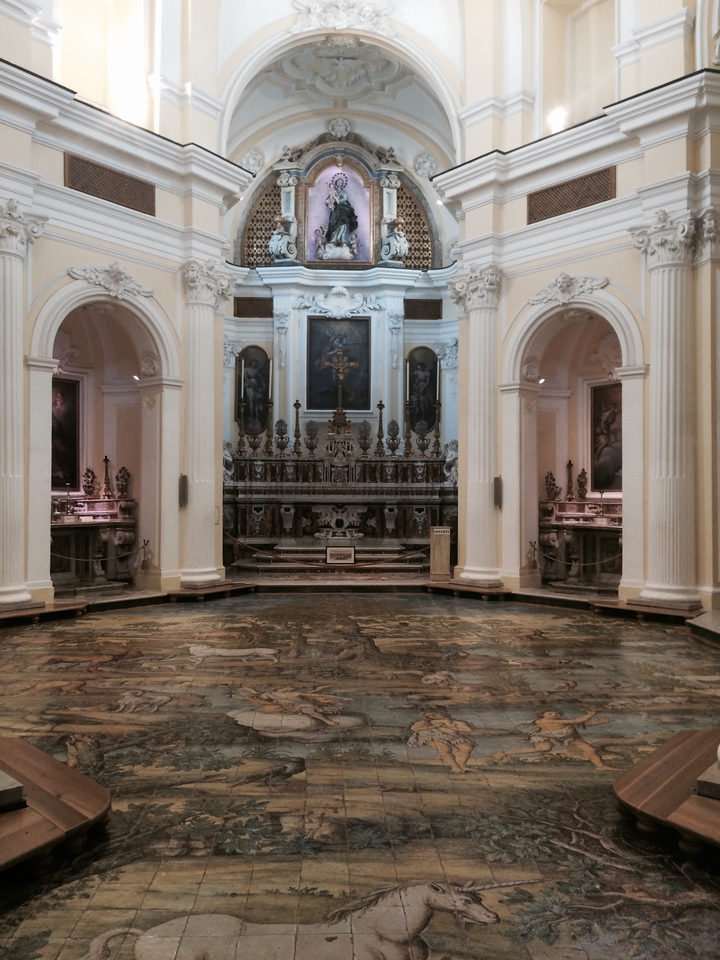 Intérieur d'une église avec autel orné et peintures sur les murs.