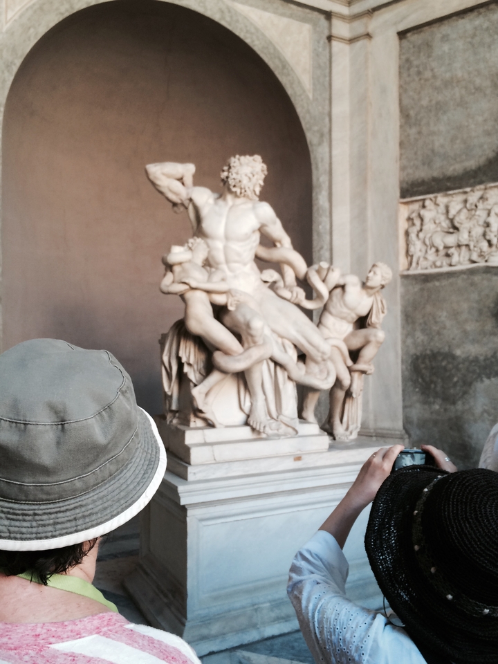 Personnes regardant une sculpture en marbre à l'intérieur d'une galerie.