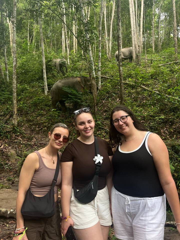 Trois personnes posant avec un éléphant dans la jungle.