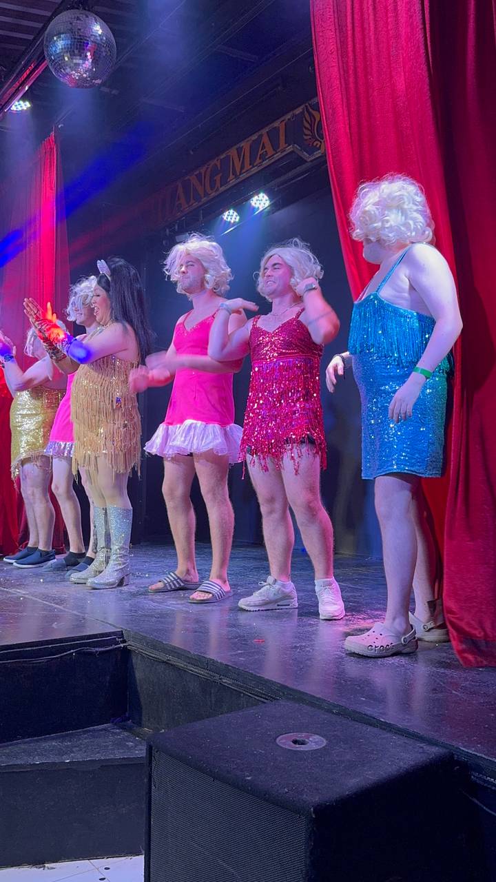 Un groupe d'artistes en robes colorées sur scène.