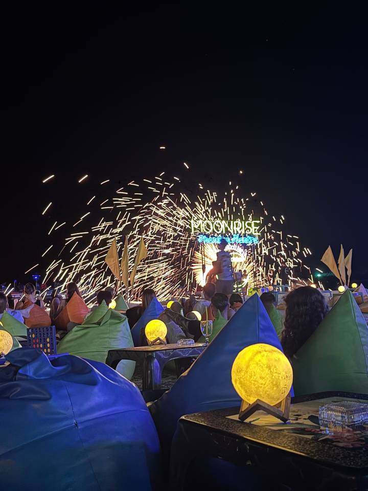 Spectacle de feu la nuit dans un cadre de plage, avec une foule qui regarde.