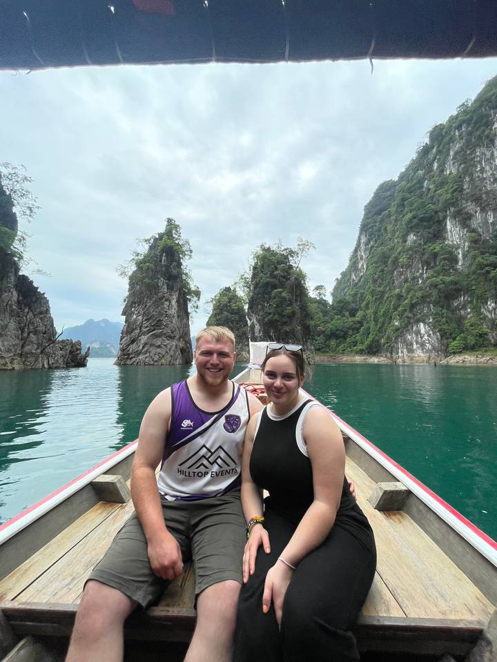 Un couple sur un bateau avec des falaises de calcaire en arrière-plan.
