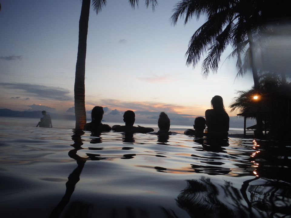 Silhouetted people enjoying a sunset in an infinity pool.