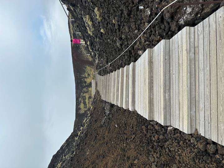 Escalier en bois menant vers le haut à travers un terrain volcanique.