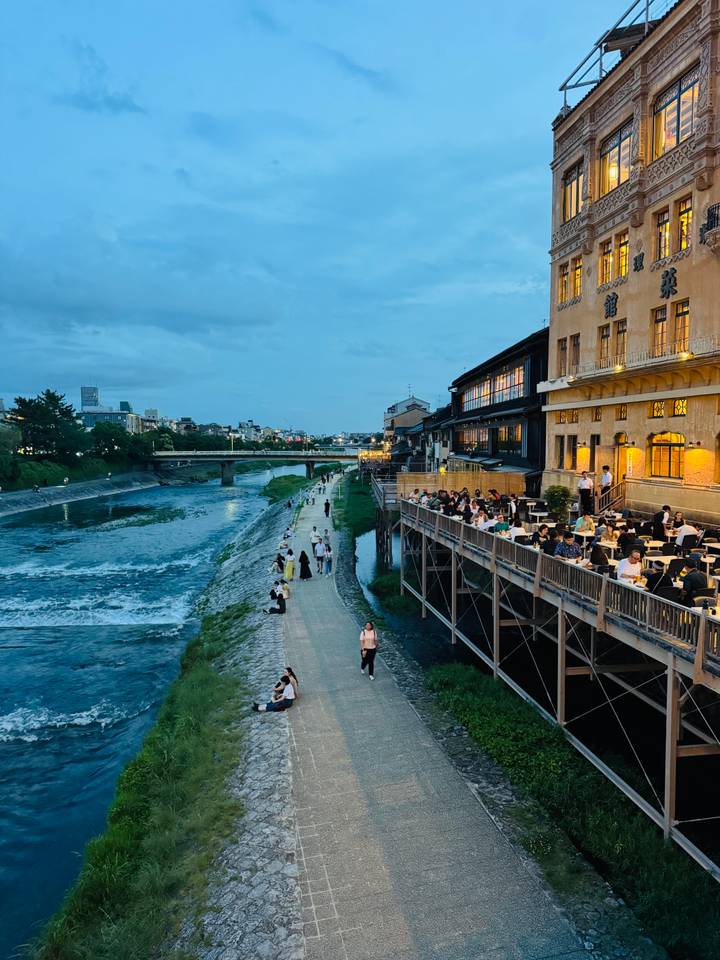 Des personnes qui dînent le long d'une rivière pendant la soirée.