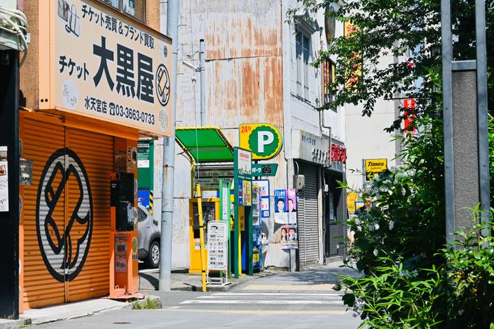 Rue urbaine colorée avec divers panneaux de magasins.