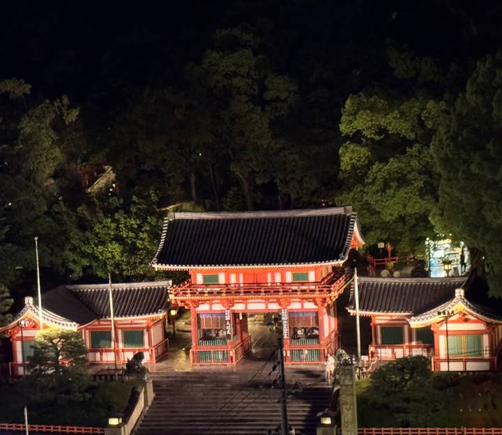 Portail traditionnel entouré d'arbres la nuit.
