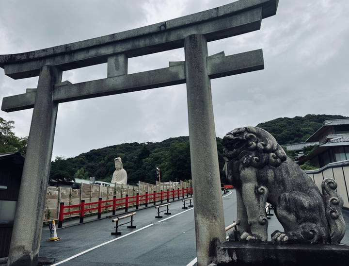 Porte torii en pierre et statue gardienne à l'entrée du sanctuaire.