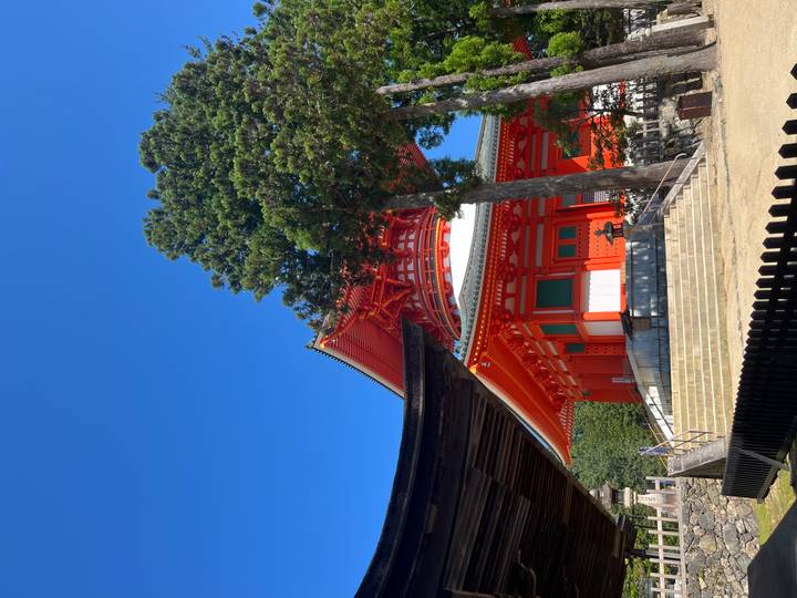 Un temple pagode rouge vif dans une zone boisée.