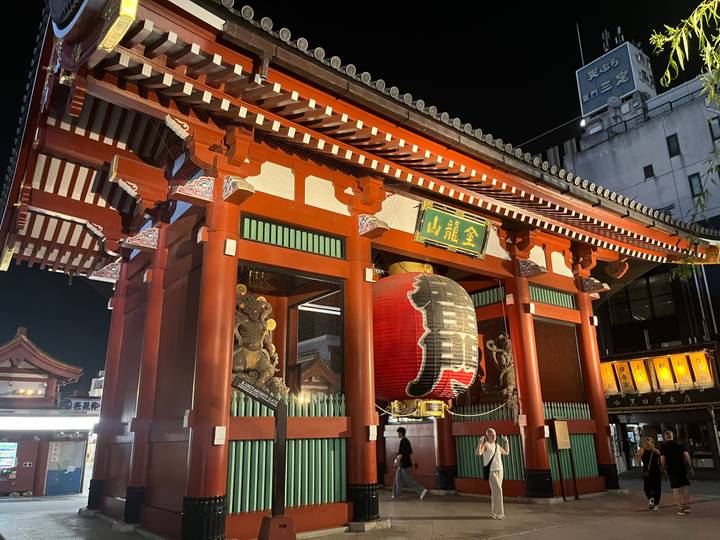 Portail illuminé la nuit avec des visiteurs devant.
