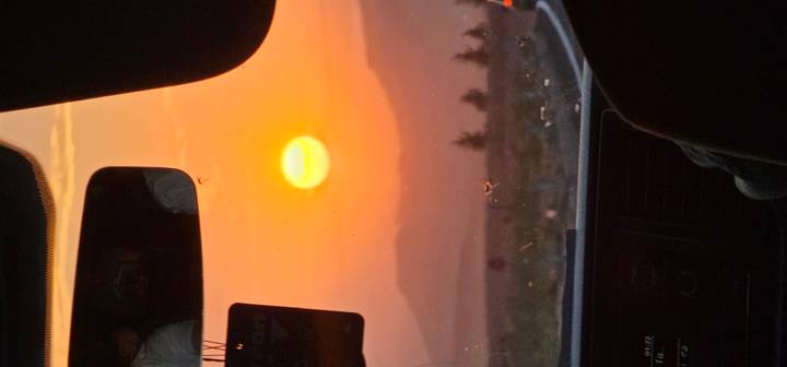 Vue du coucher de soleil à travers un pare-brise de voiture.