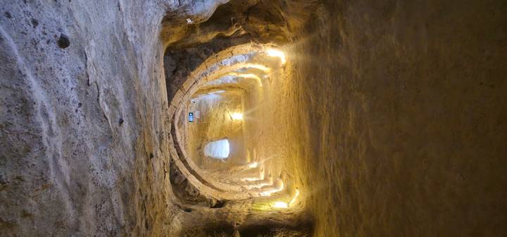 Tunnel souterrain avec murs en pierre et chemin éclairé.