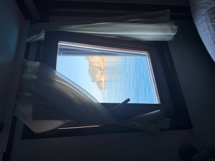 Vue d'une fenêtre en mer avec la terre au loin.