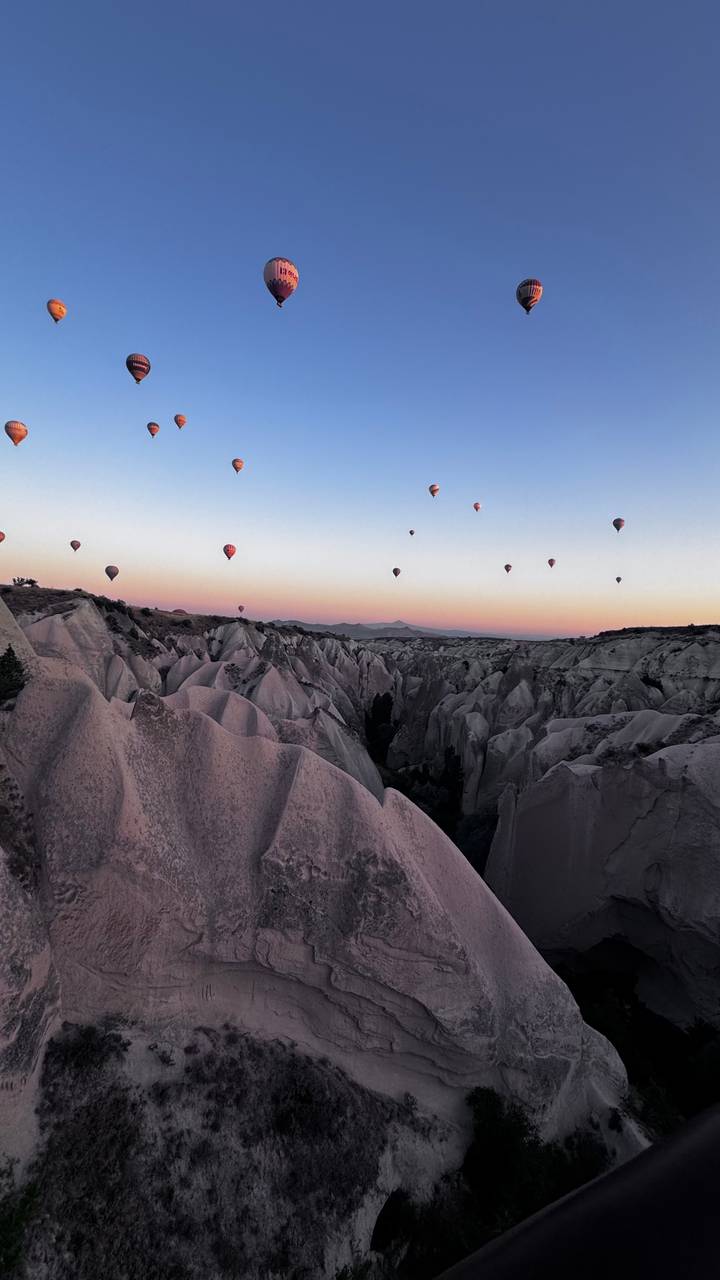 Montgolfières au-dessus d'un paysage rocheux au coucher du soleil.