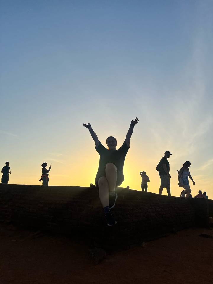 Une personne en silhouette contre un ciel de coucher de soleil lumineux.