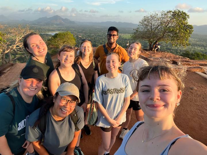 Un groupe de personnes posant avec une vue panoramique sur la terre et l'eau.