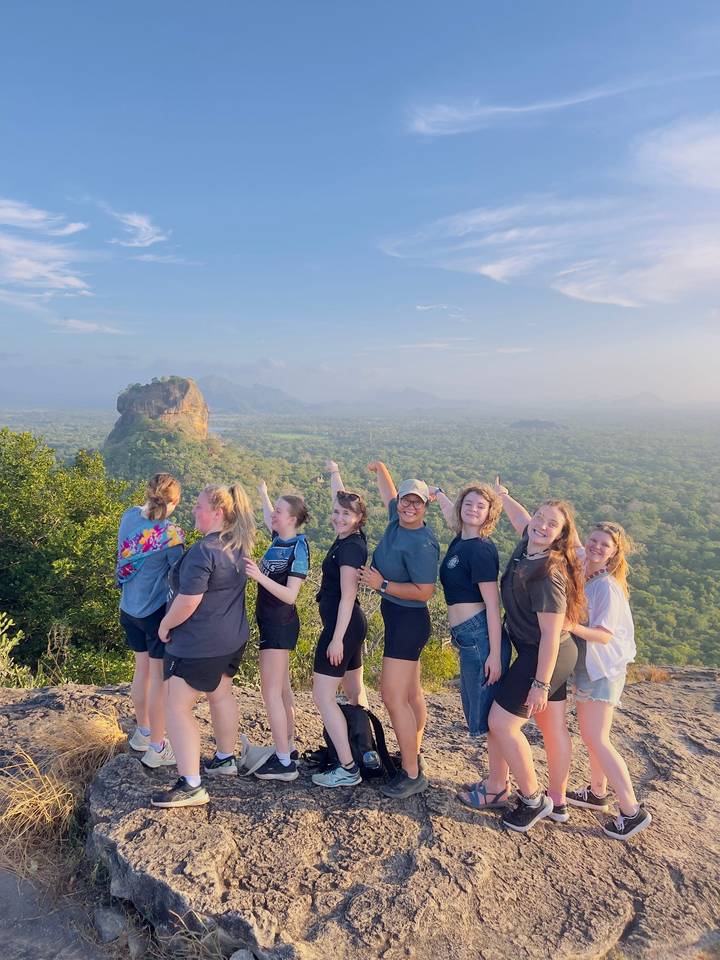 Un groupe de personnes pointant vers le rocher de Sigiriya avec un paysage luxuriant.