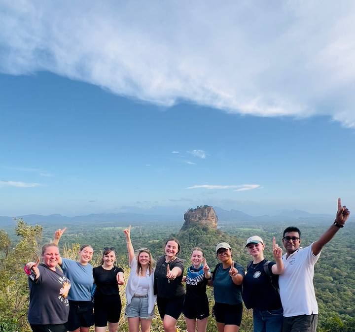 Un groupe de personnes posant avec le rocher de Sigiriya en arrière-plan.