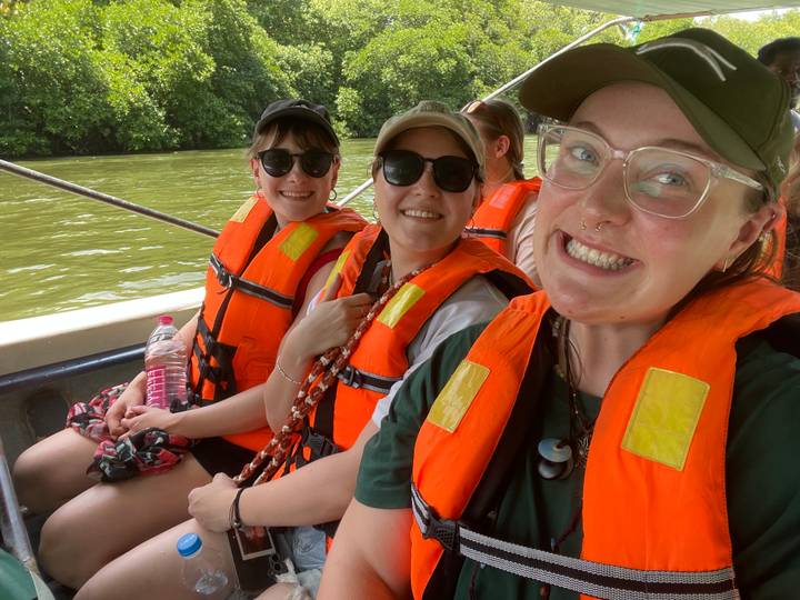 Trois personnes dans un bateau portant des gilets de sauvetage.