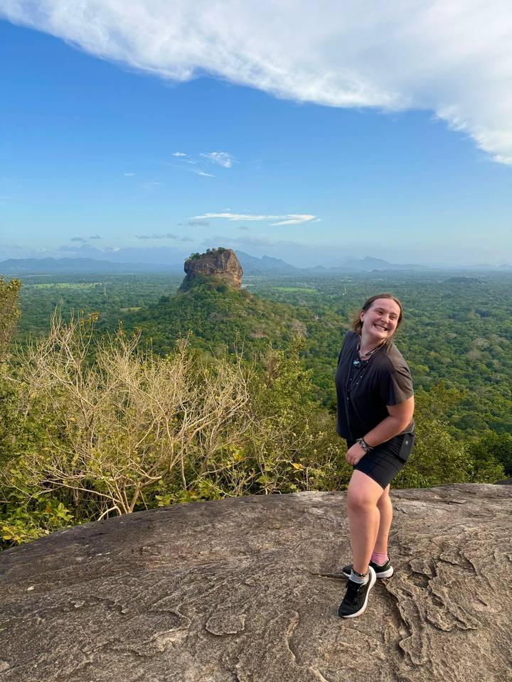 Une personne qui pose avec le rocher de Sigiriya en arrière-plan.