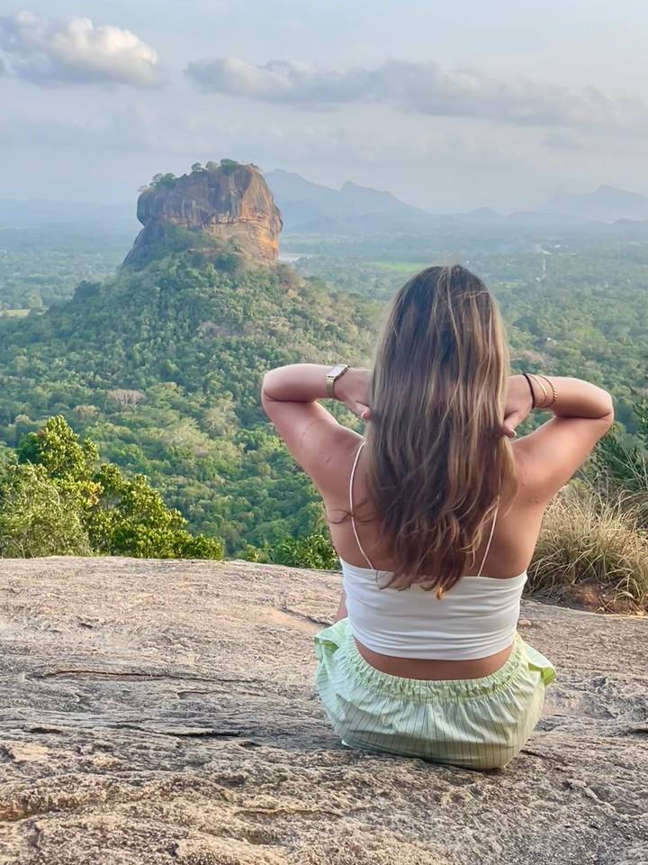 Une femme regardant une montagne lointaine couverte de forêt.