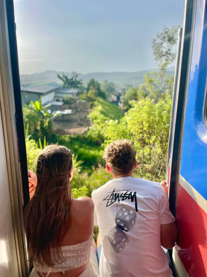 Deux personnes se penchant hors d'un train profitant de la vue sur le paysage.