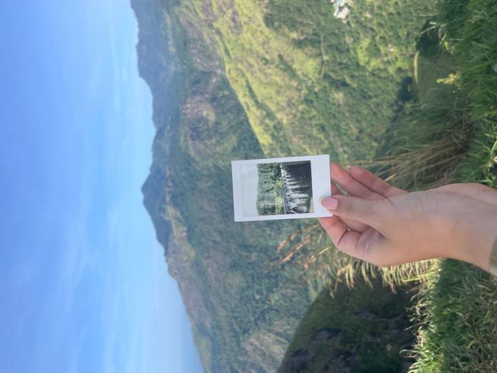 Une personne tenant une photo polaroid avec une vue de montagne.