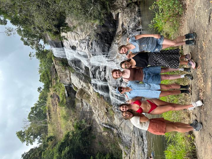 Photo de groupe de six femmes debout devant une cascade.
