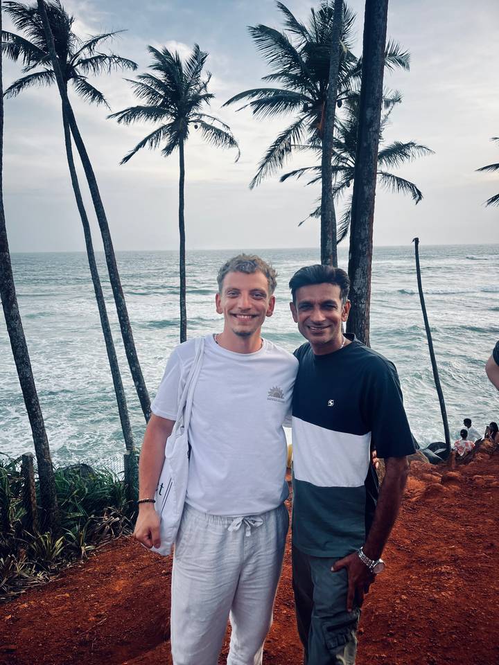Deux personnes souriantes face à la caméra avec la mer en arrière-plan.