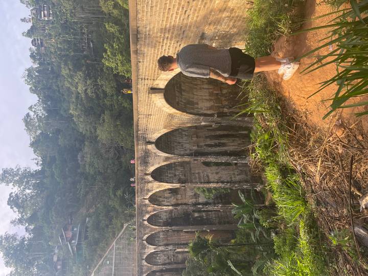 Homme debout au bord surplombant un viaduc historique.